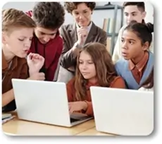 Grupo de niños frente a una notebook acompañados por una docente joven